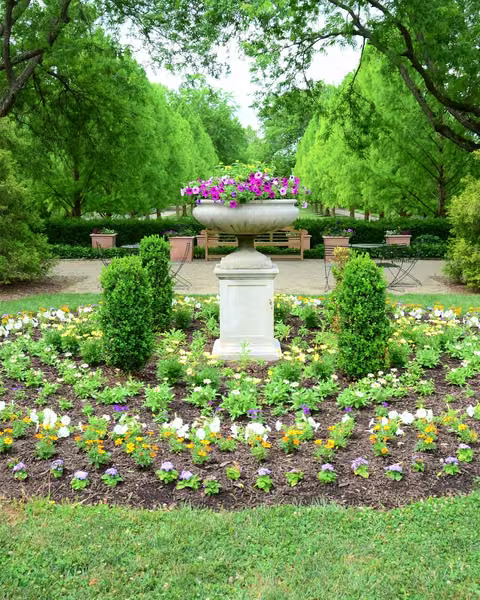 Circular parterre flower bed with a stone urn centerpiece