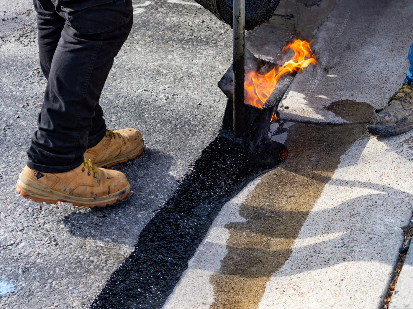 Hot-pour crack sealing being applied to a cracked commercial parking lot