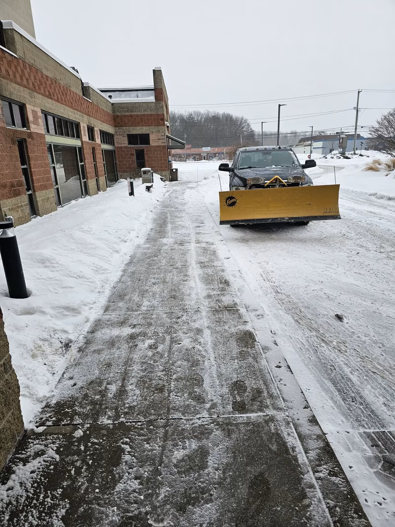 Terravian plow truck clearing the entrance walk of a commercial building after a snowfall